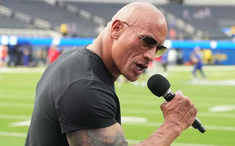 Dwayne "The Rock" Johnson holding a microphone on a football field